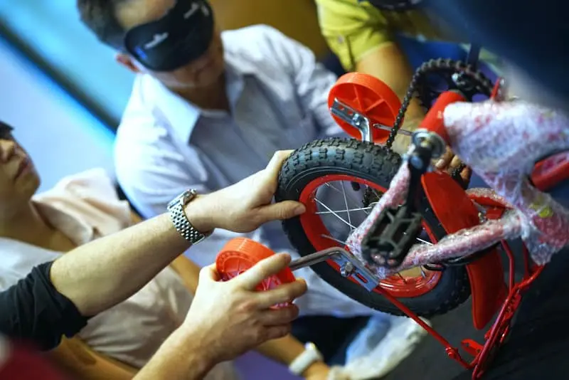 Group holds a red bike to assemble it