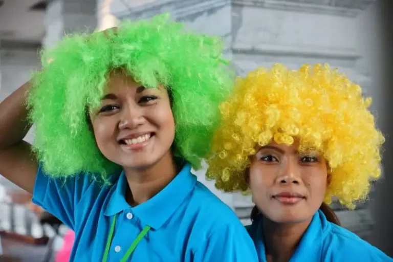 Two actresses wearing prop colourful wigs
